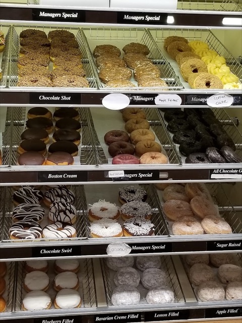 The donut case at the Torrington shop: labeled rows of Boston cream, chocolate frosted, jelly and sugar-raised donuts